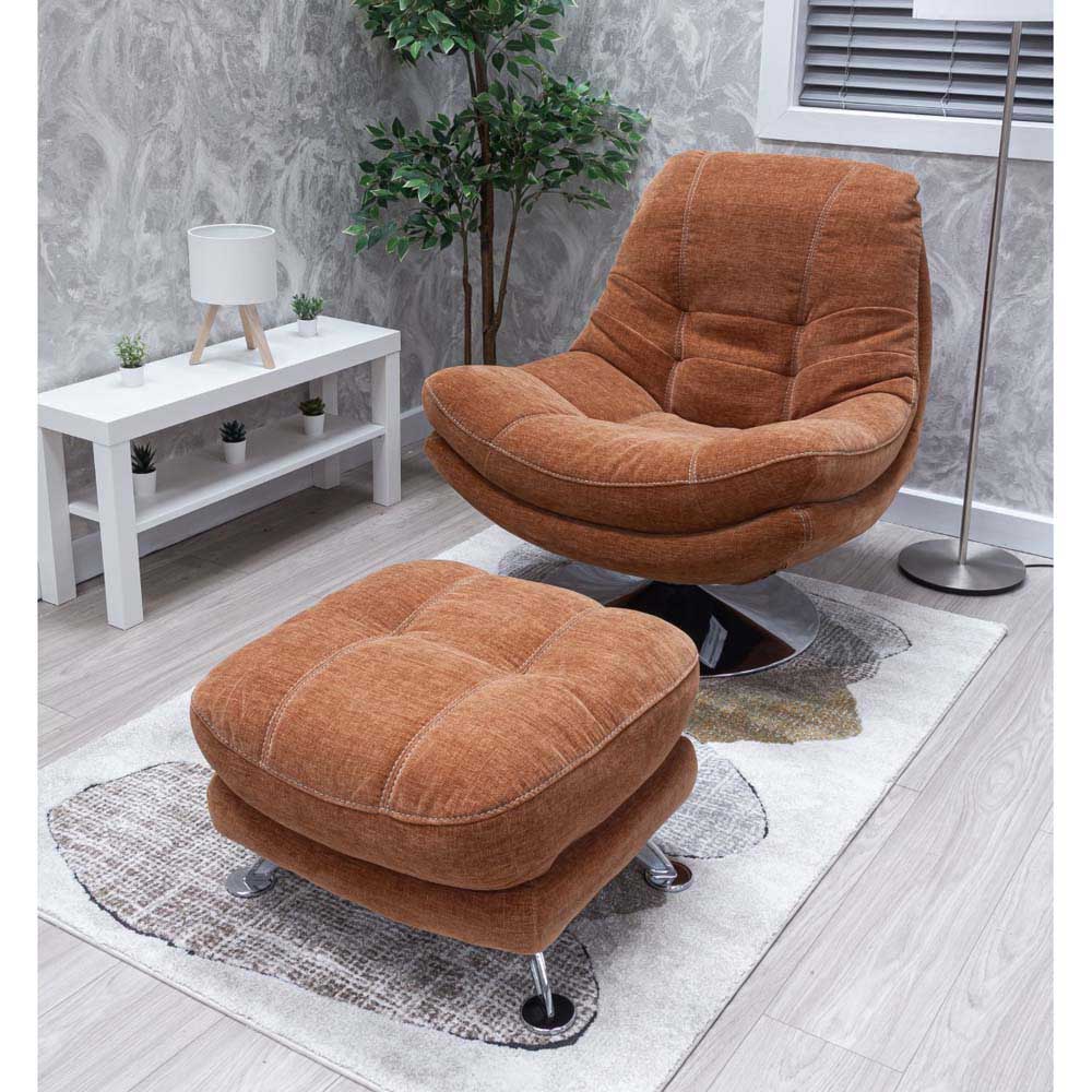 Copper orange occasional chair and footstool in a room with a white table and plant.