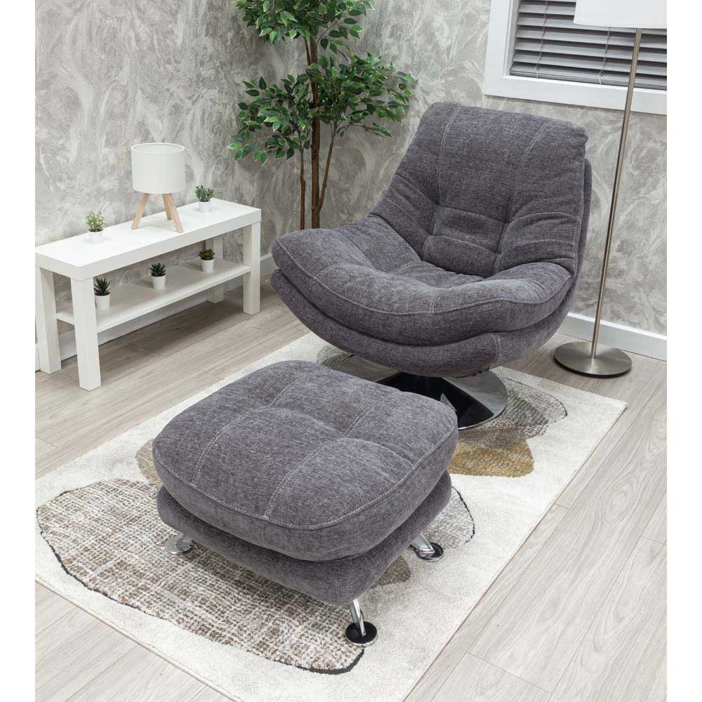Gray armchair and footstool set in a room with a white table and plant.