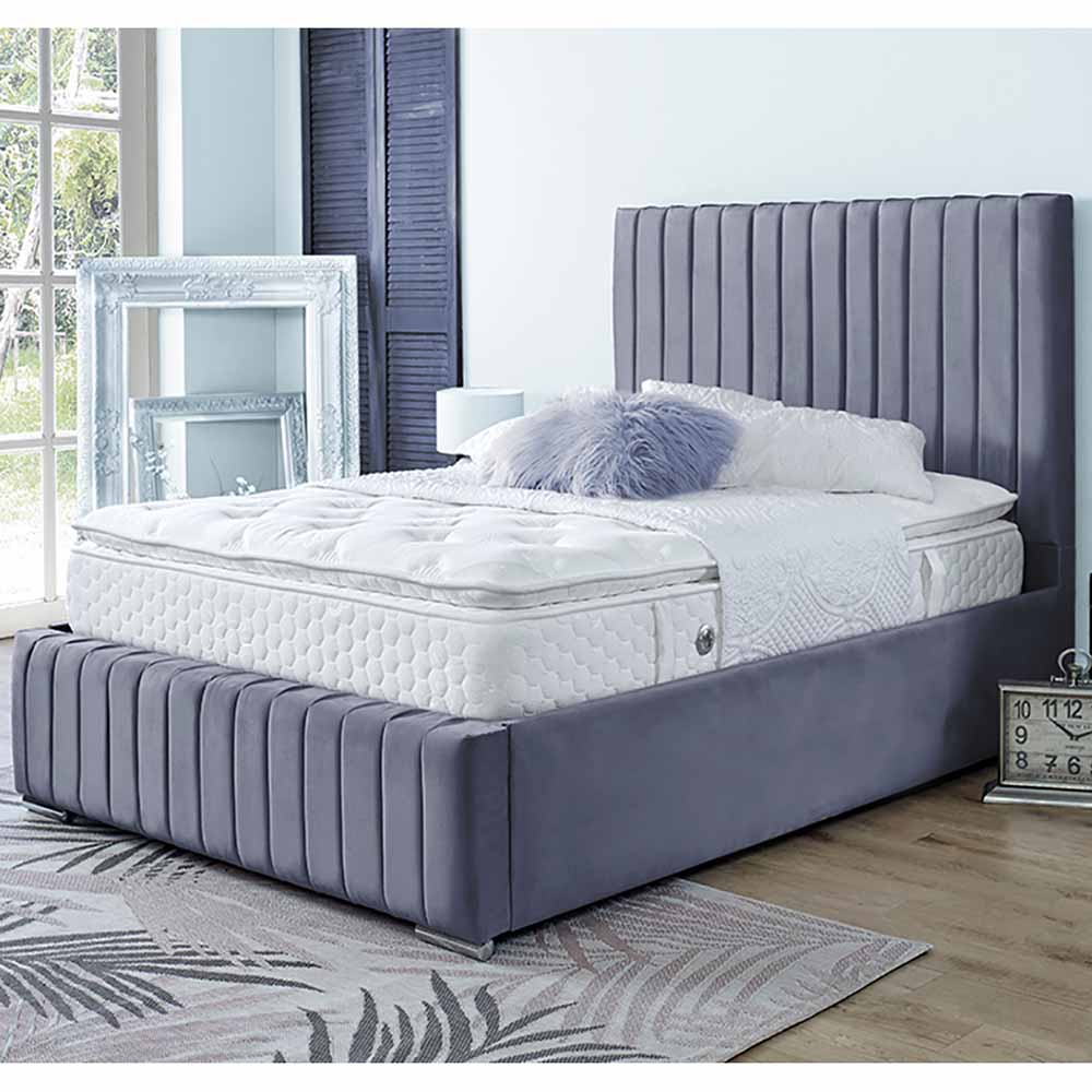 Gray upholstered bed with white mattress in a room with large windows.
