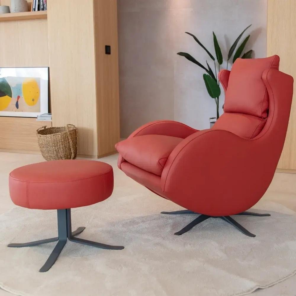 A modern red upholstered recliner chair with a matching round footstool, both on dark metal swivel bases, shown in a styled living room setting.