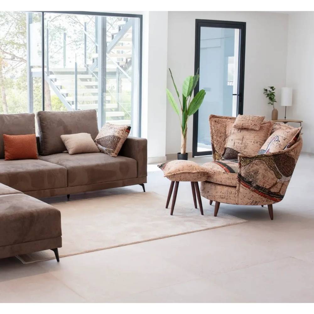 A modern living room setup featuring a brown fabric sofa with patterned accent pillows, and a distinctive asymetrical curved back armchair upholstered in a multicolor map-like patterned fabric, all arranged on a light beige rug in a bright, contemporary room.