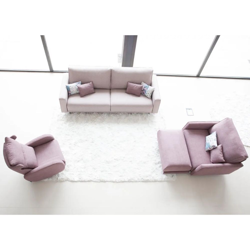 A minimalist living room setup featuring a light pink sofa, a matching pink recliner, and love seat and a white shag rug under large windows.