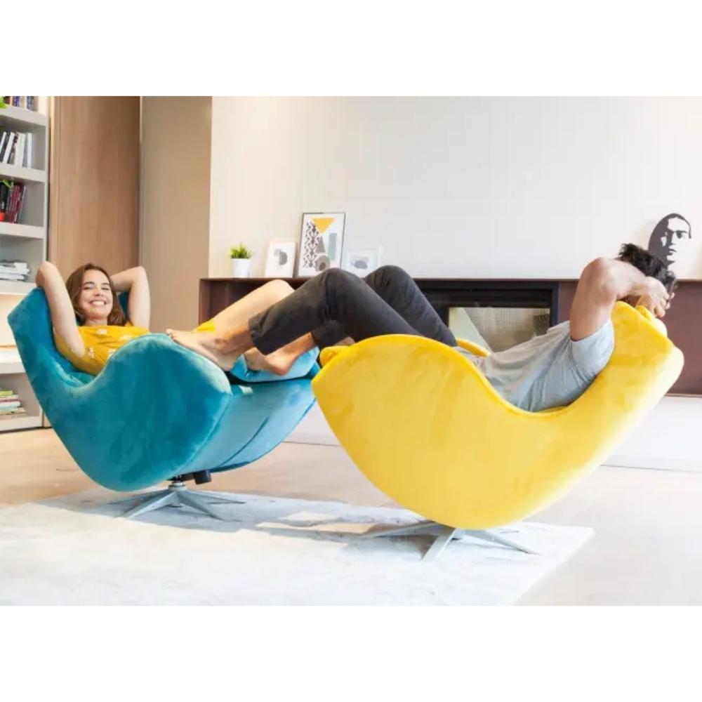 Two modern curved lounge chairs in bright teal blue and yellow, each with a person reclining on them in a living room setting.