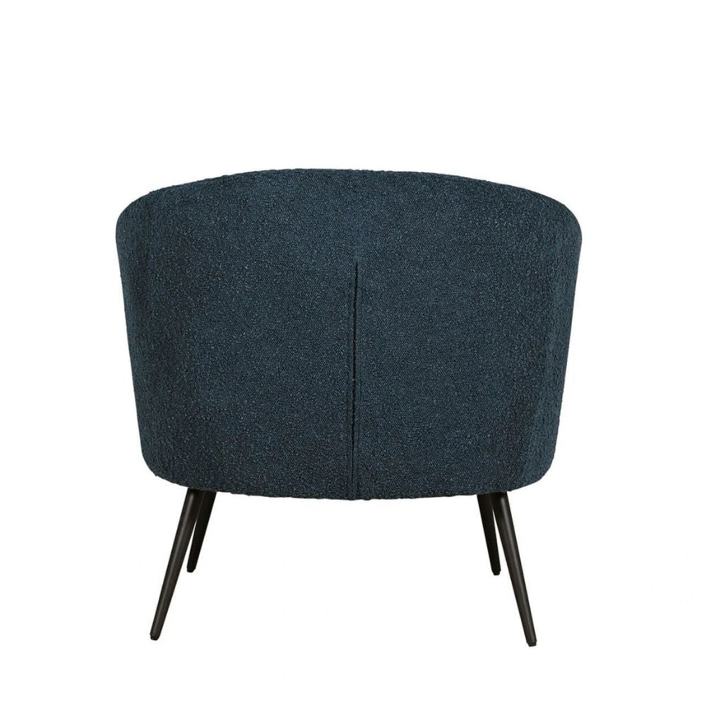 A modern barrel-style armchair upholstered in a textured dark blue bouclé fabric, featuring a vertical seam down the center and tapered black metal legs, shown against a plain white background.