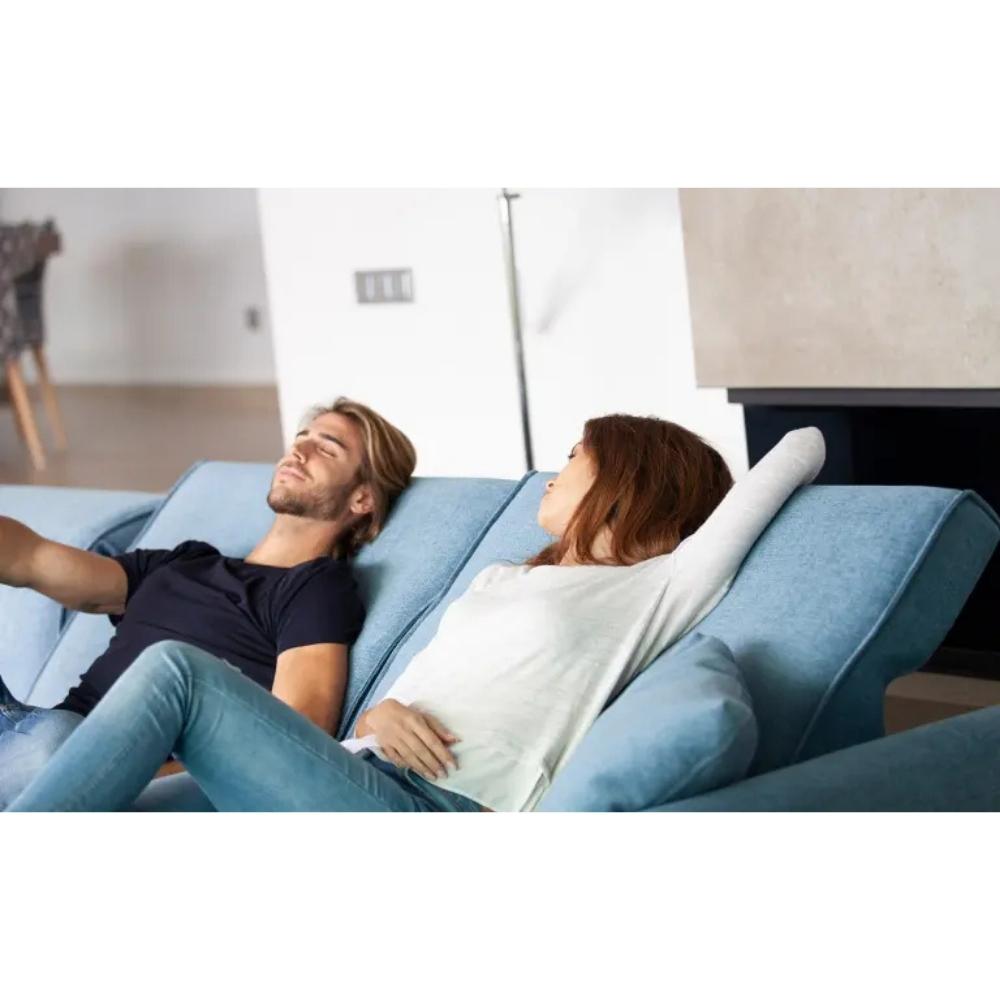 A man and a woman relax on a light blue sectional sofa in a modern living room setting.