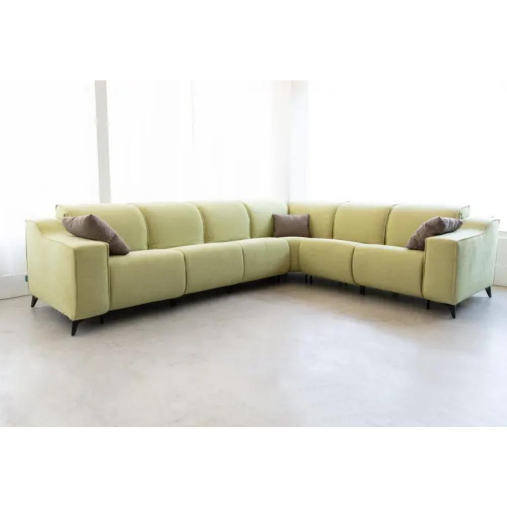 A light yellow-green modular L-shaped sectional sofa with three brown accent pillows, shown in a minimalist room with a light gray floor and white walls.