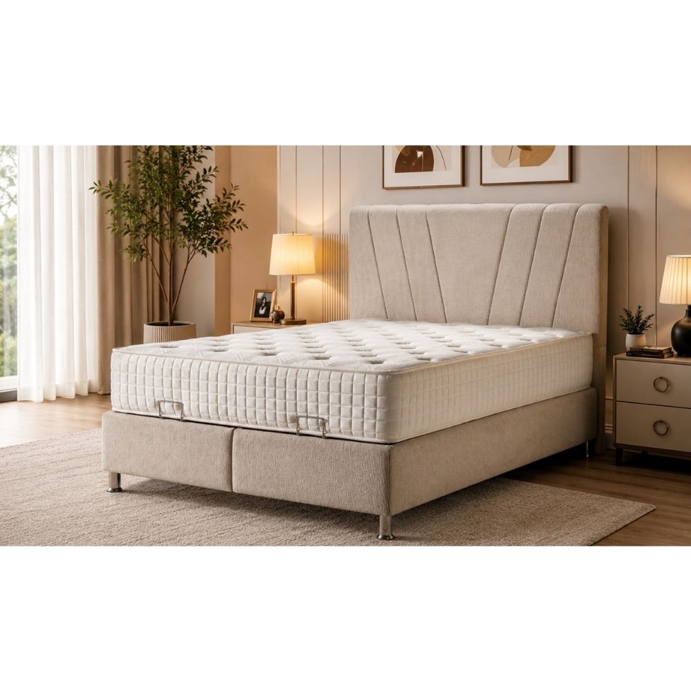 A bed with a quilted white mattress and a beige upholstered headboard and base, shown in a styled bedroom setting with bedside tables, lamps, wall art, and a plant.