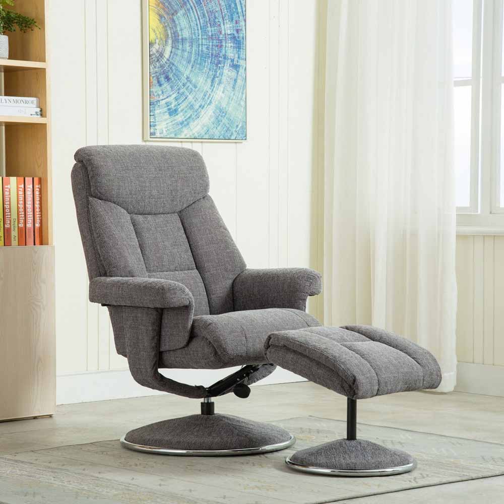 Gray recliner chair with footstool in a room with books and a painting on the wall.