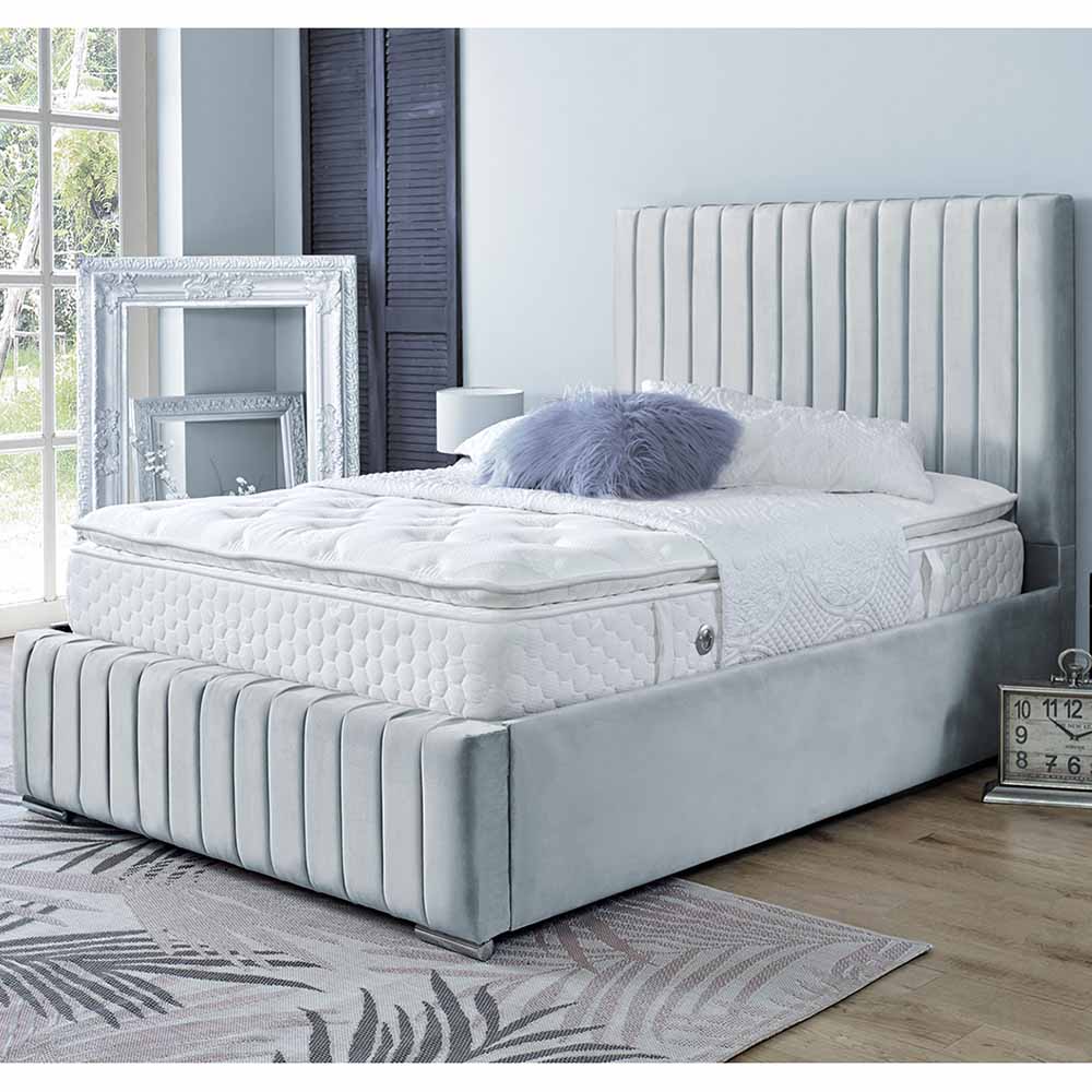 Silver upholstered bed with white mattress in a bedroom setting