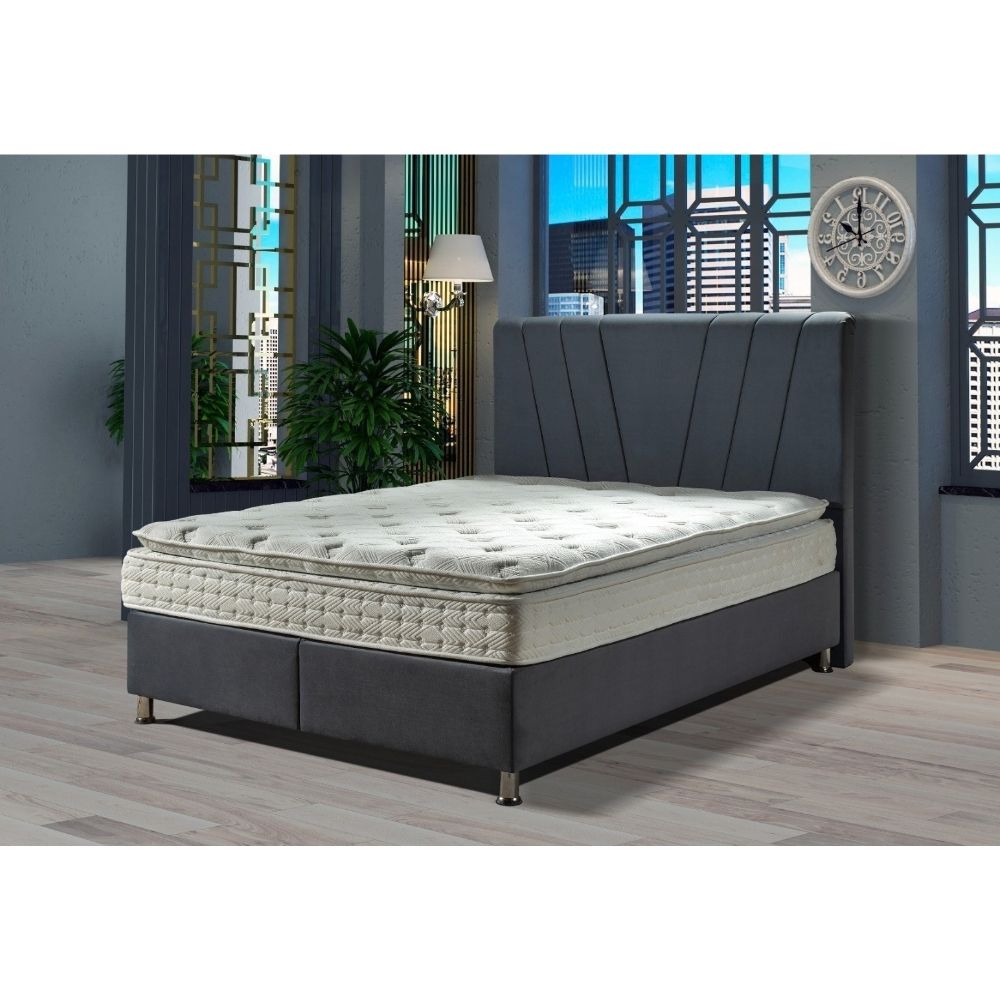 A dark gray upholstered bed frame with a tall segmented headboard and a white tufted mattress, shown in a modern bedroom setting with gray walls, wood flooring, and window views.