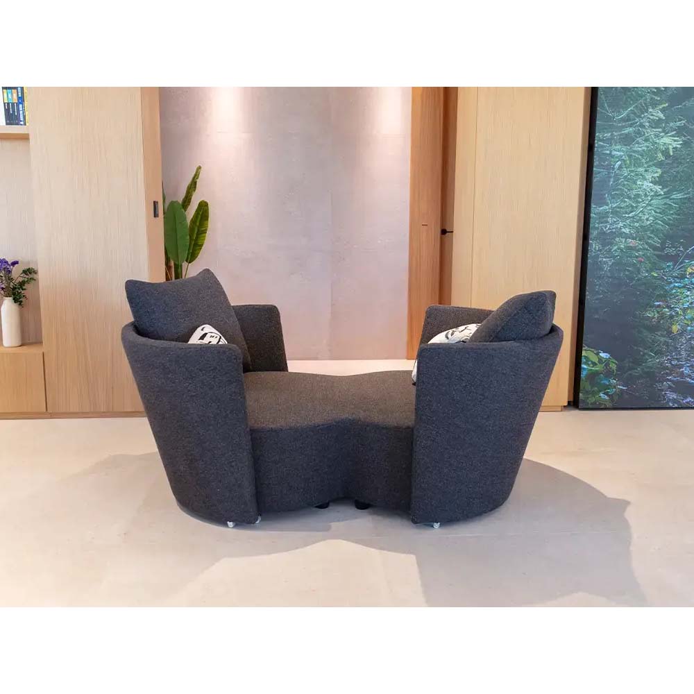 Modern gray infinity sofa with cushions in a room with wooden walls and a large screen.