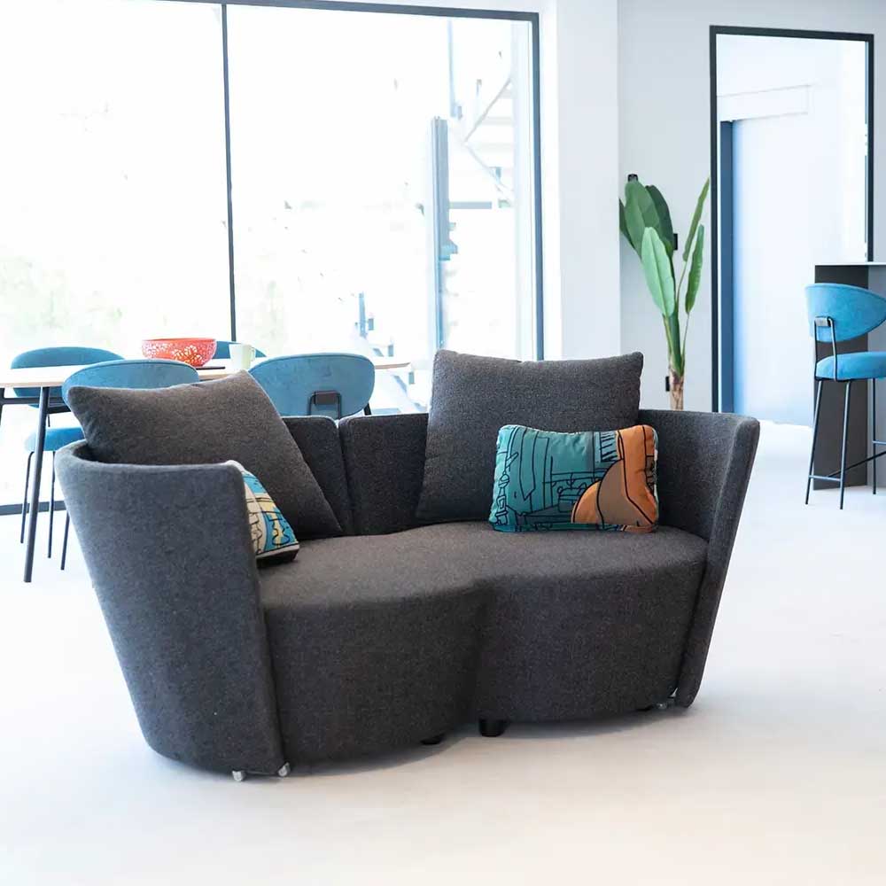 Gray infinity sofa with colorful cushions in a modern room with large windows.