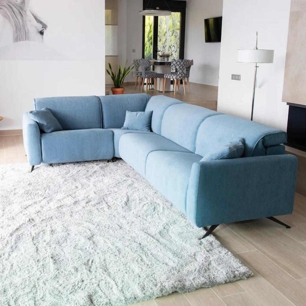 A light blue modular L shaped sectional sofa with matching throw pillows, styled on a large white shag rug in a modern living room setting.