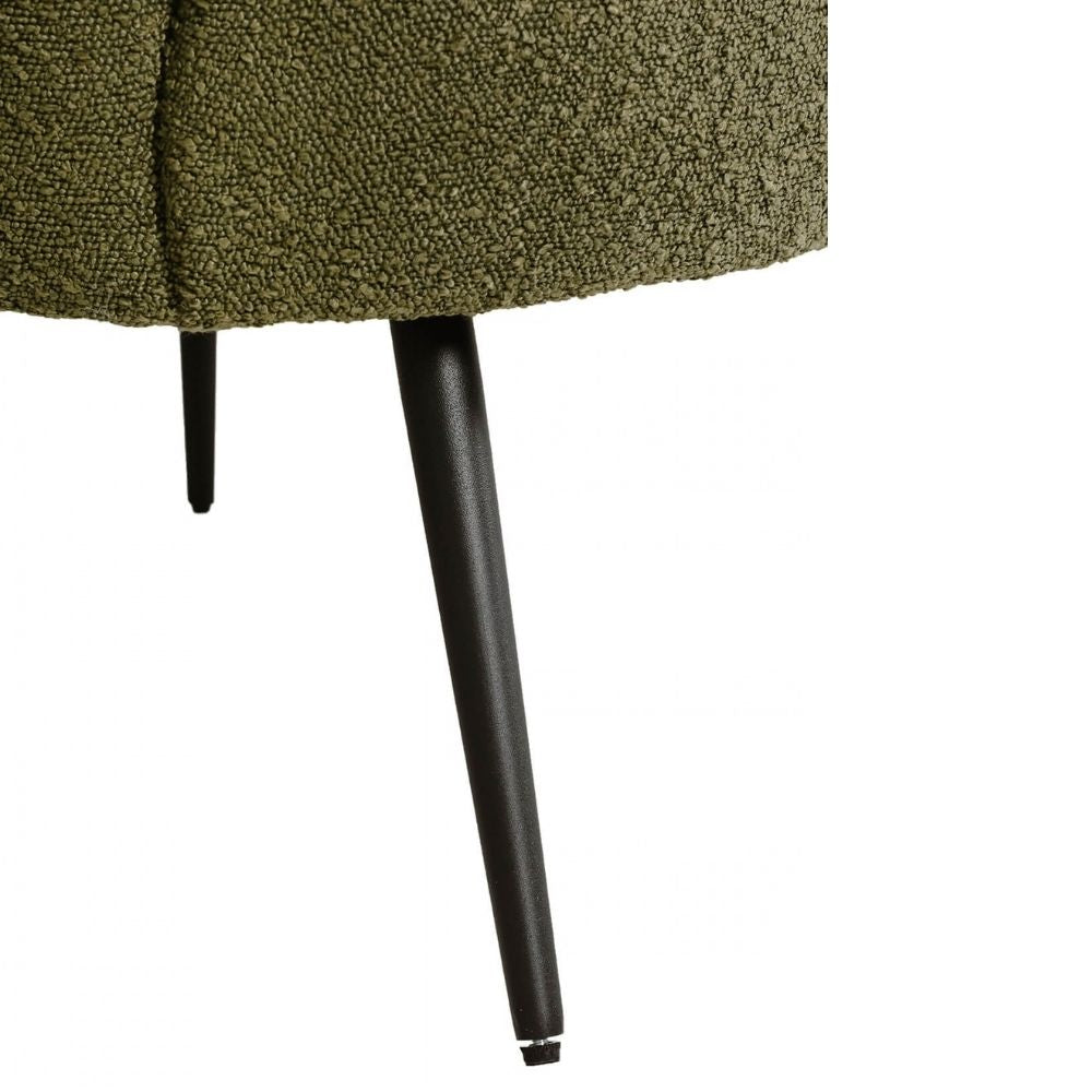 Close-up of an upholstered furniture piece in textured olive green fabric with tapered black legs, shown against a plain white background.