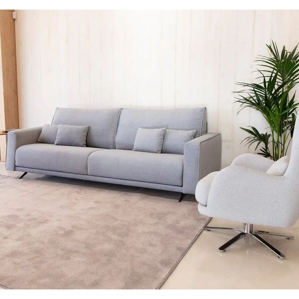 A light gray fabric sofa with matching throw pillows in a modern living room setting, next to a white swivel armchair and a green potted plant.