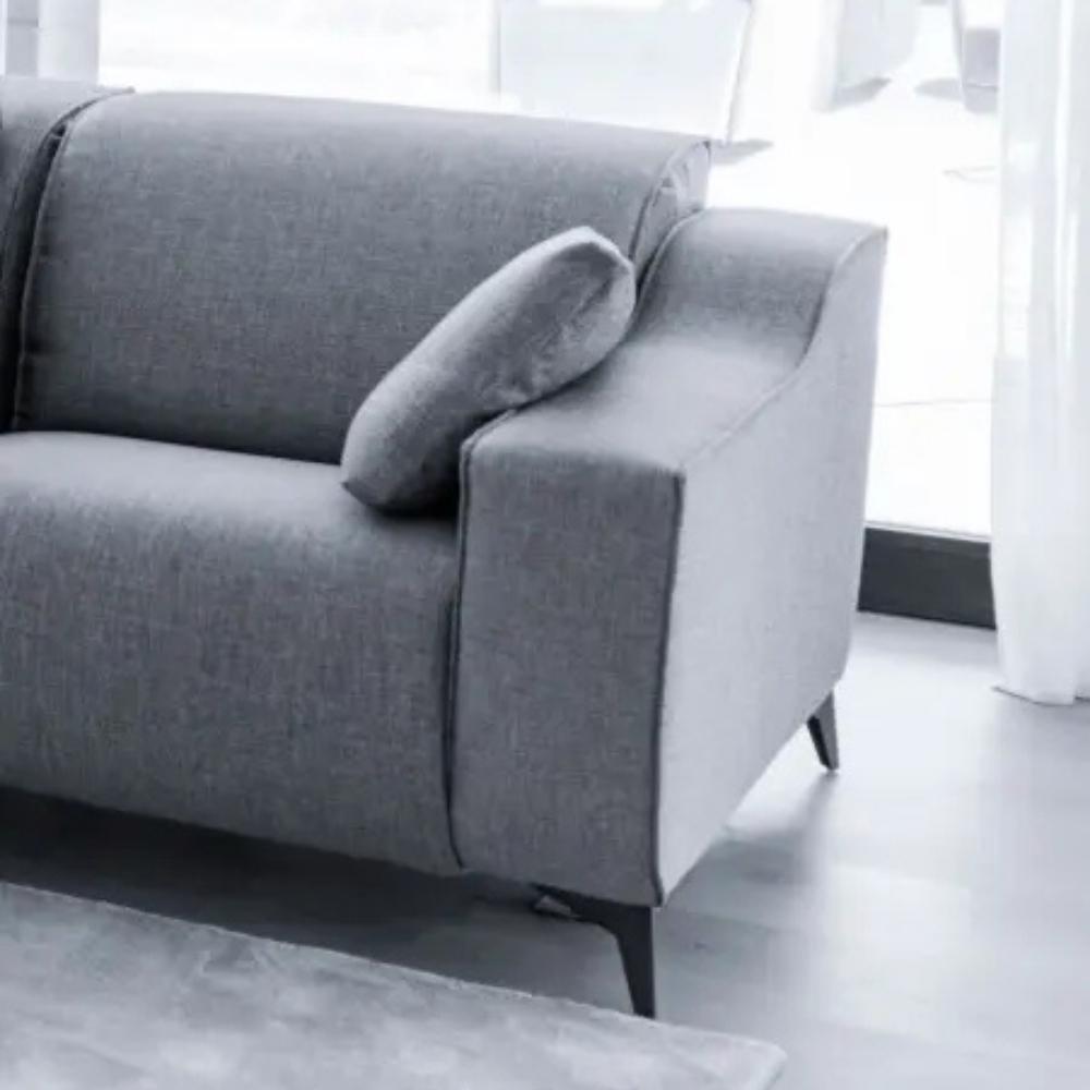 A modern gray fabric loveseat sofa with a matching throw pillow, shown in a bright, minimalist living room setting.