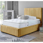 Mustard upholstered bed with white mattress in a room with large windows and decorative elements.