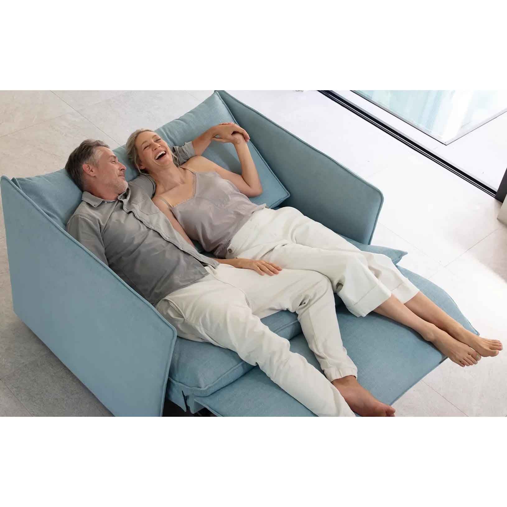 Two people lying on a light blue sectional sofa in a modern living room.