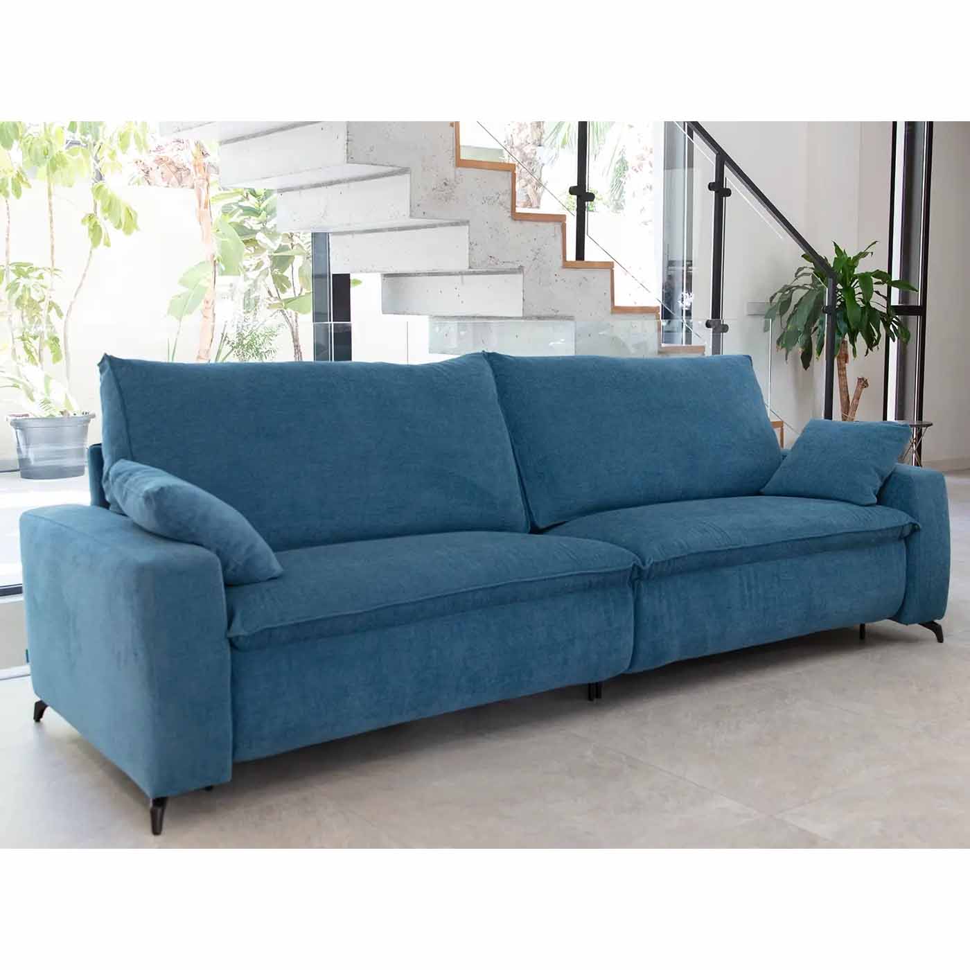 Blue sofa in a modern living room with a staircase and plants.