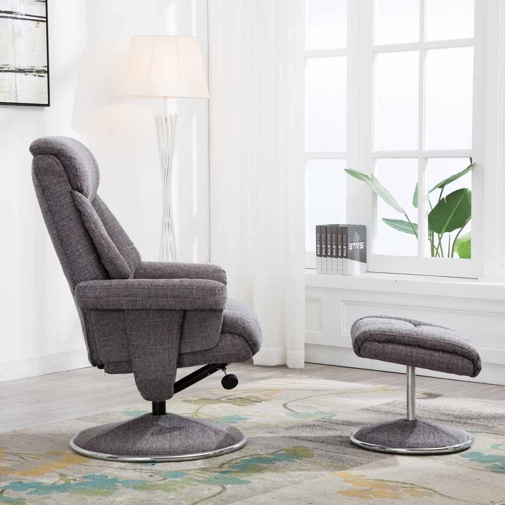 Gray recliner chair with footstool in a room with a lamp and window.