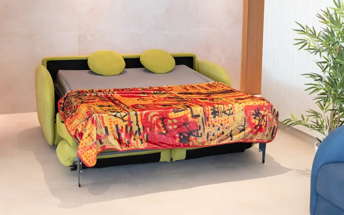 Sofa bed with colorful blanket and green cushions in a room setting.