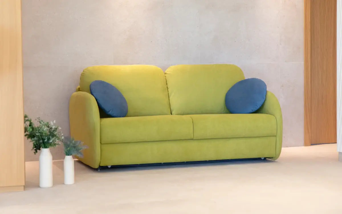 Green sofa with blue cushions in a minimalistic room.