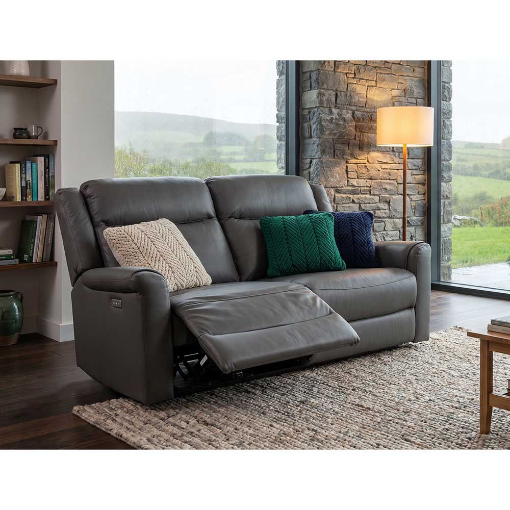 Gray leather electric recliner sofa in a living room with pillows and a lamp.