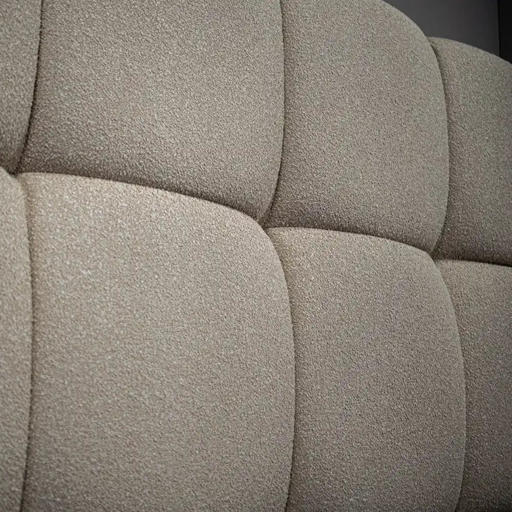 Close-up of textured gray or beige fabric headboard with a tufted pattern