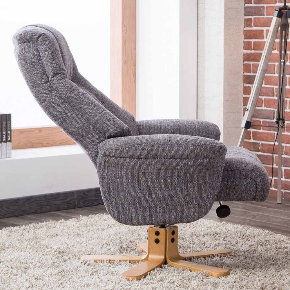 Gray recliner chair with wooden base in a room with a brick wall and window.