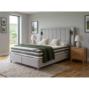 Bedroom with a bed featuring a mattress and green blanket, wooden nightstands, and framed pictures on the wall.