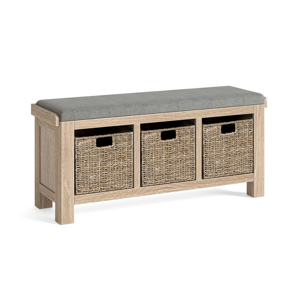 Wooden storage bench with a grey cushion top and three wicker basket drawers on a white background.