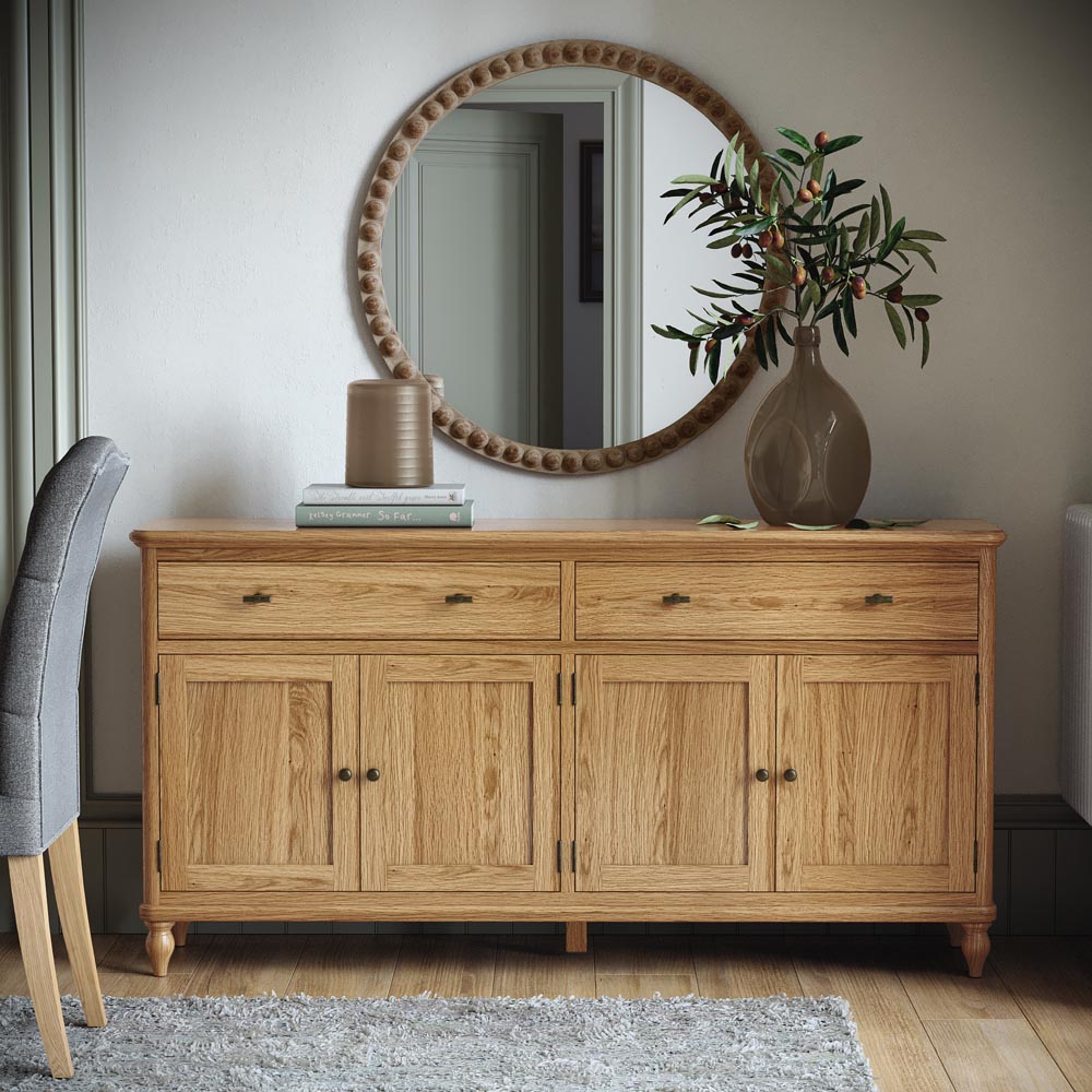 Wooden sideboard with round mirror and decorative items in a room setting