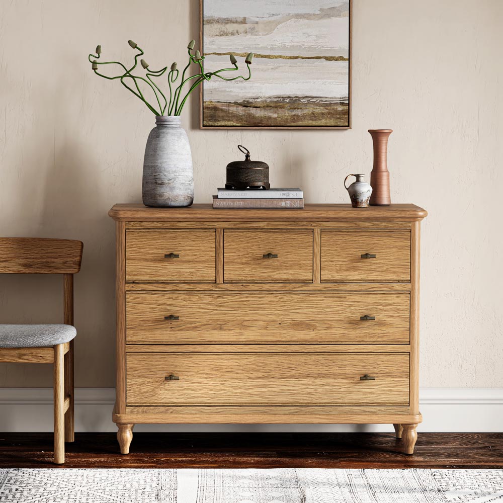 Wooden 5 drawer dresser (3 over 2) with decorative items in a room setting