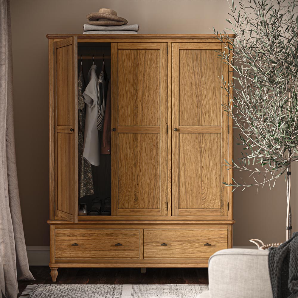 Wooden wardrobe with open doors in a room with a plant and a hat on top.