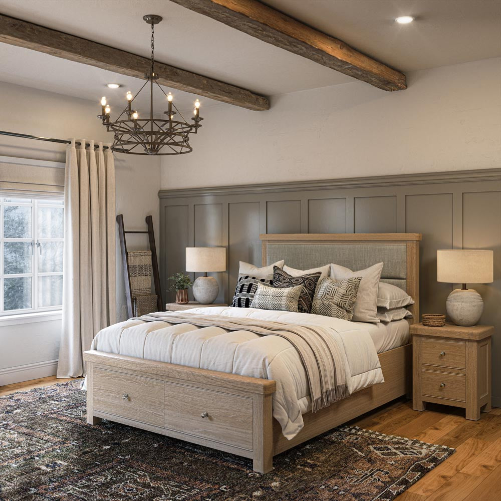 Neatly made bed in a bedroom with wooden headboard and nightstands, decorative pillows, and a chandelier.