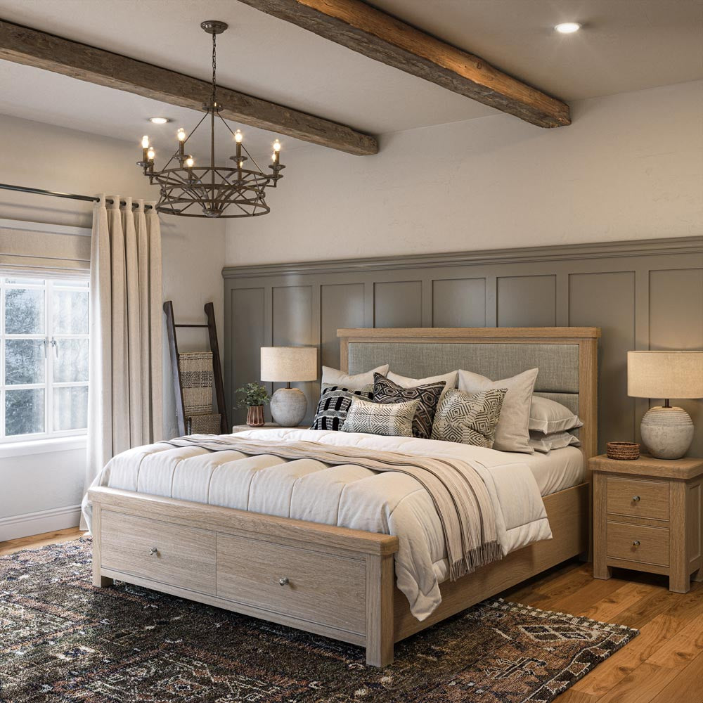 Neatly made bed in a bedroom with wooden headboard and nightstands, decorative pillows, and a chandelier.