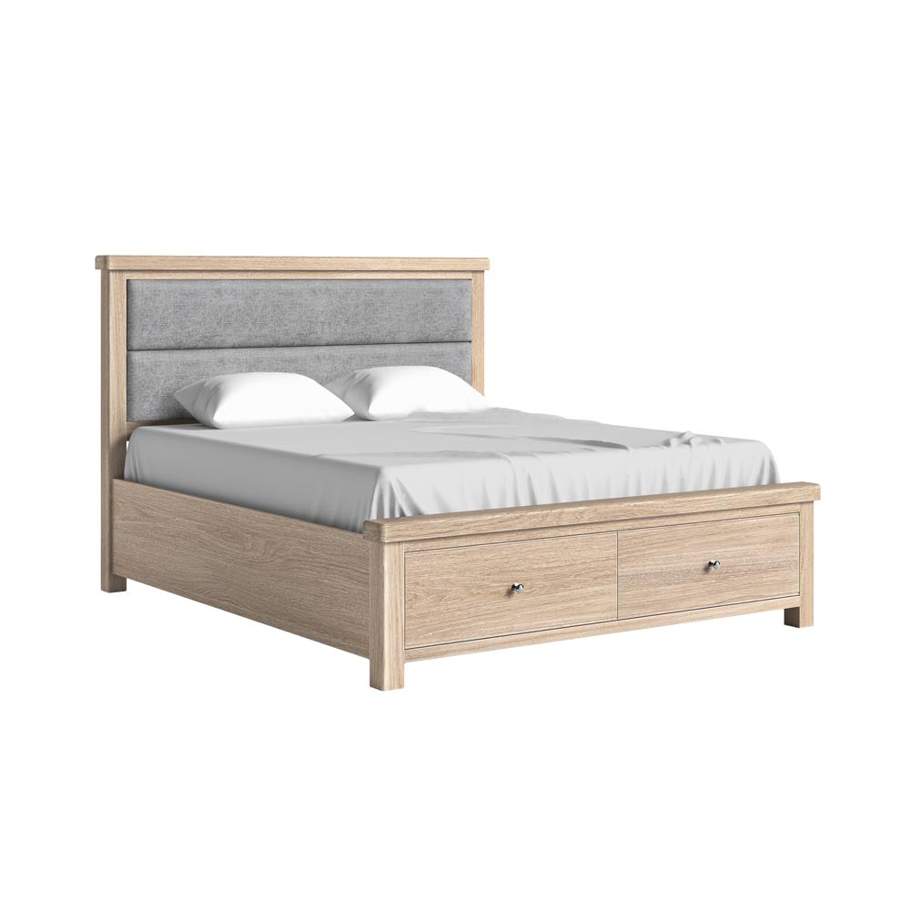 Wooden bed with gray upholstered headboard and drawers with white bedding on a white background