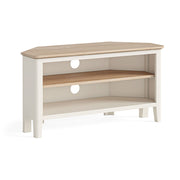 corner tv unit, white, with oak top and one shelf creating 2 open shelf spaces. Open shelving below top. 2 circular holes in the back of the unit for wires to be connected to tv, games consoles etc... angled view of the unit.