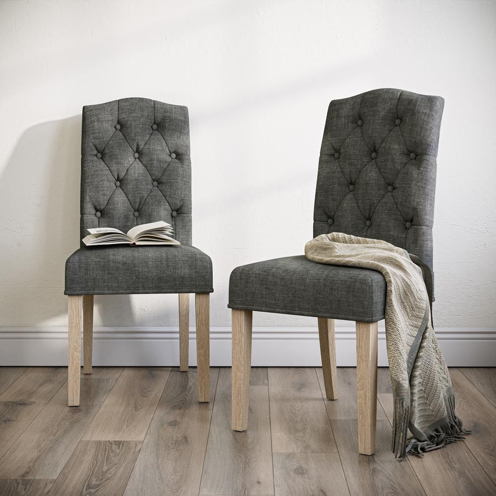 Two grey upholstered chairs with wooden legs on a wooden floor.