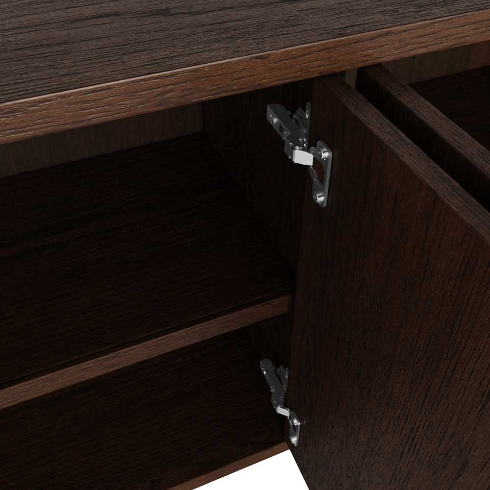 Close-up of a dark brown wood cabinet door with a silver metal hinge attached to the side, showing the cabinet interior and shelf.