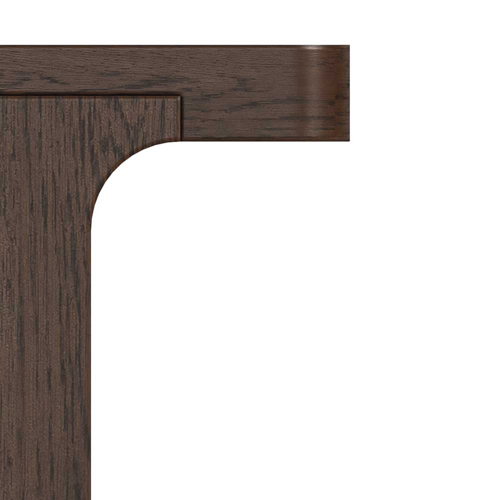 Close-up of a dark brown wooden furniture corner showing the tabletop edge and curved apron detail against a white background.