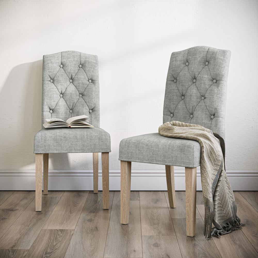 Two beige upholstered chairs with wooden legs on a wooden floor.