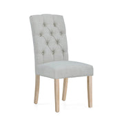 Beige upholstered chair with button tufting on a white background