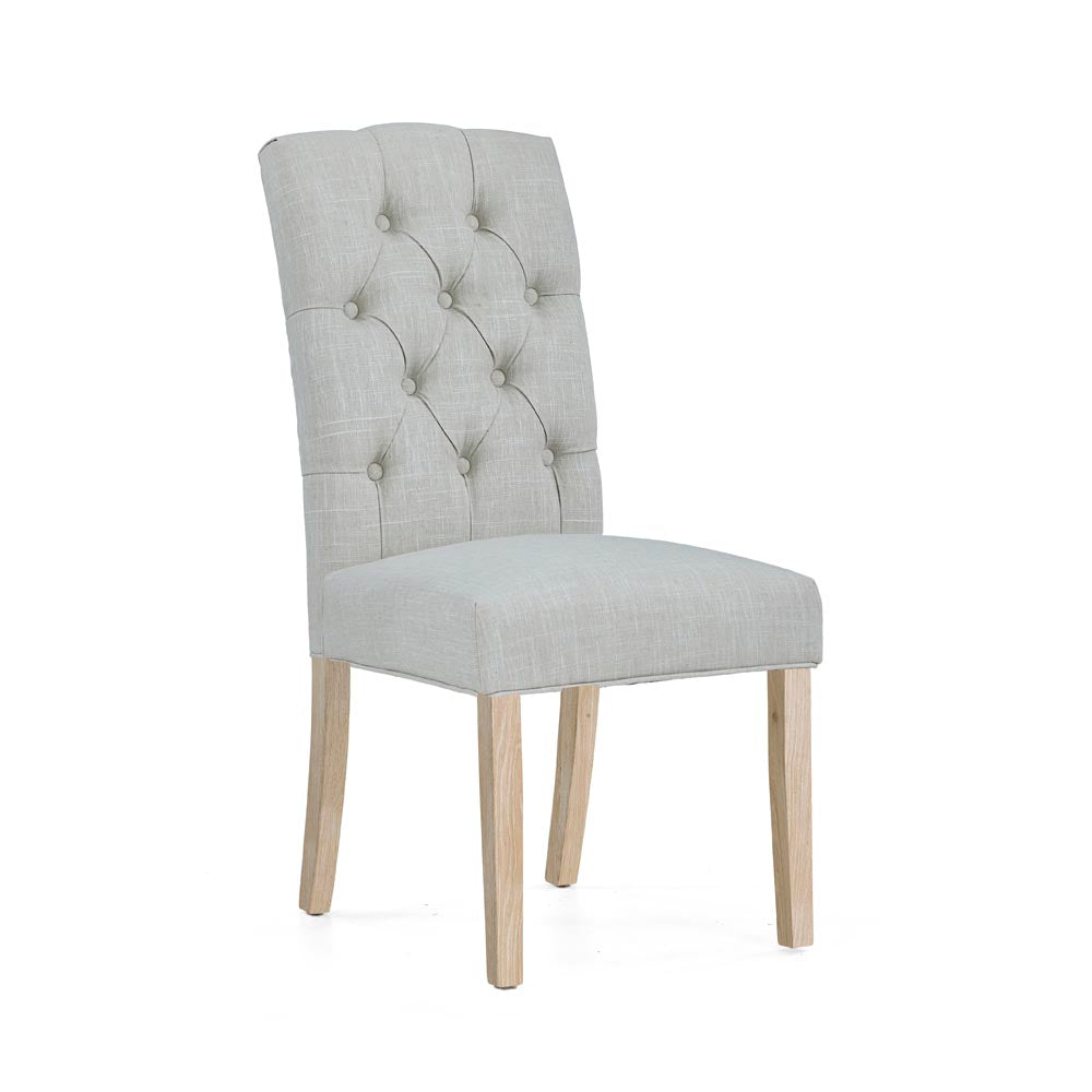 Beige upholstered chair with button tufting on a white background