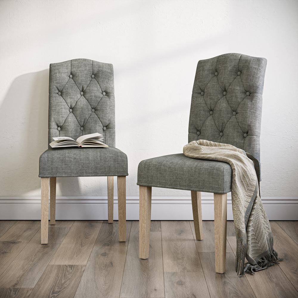 Two grey upholstered chairs with wooden legs on a wooden floor.
