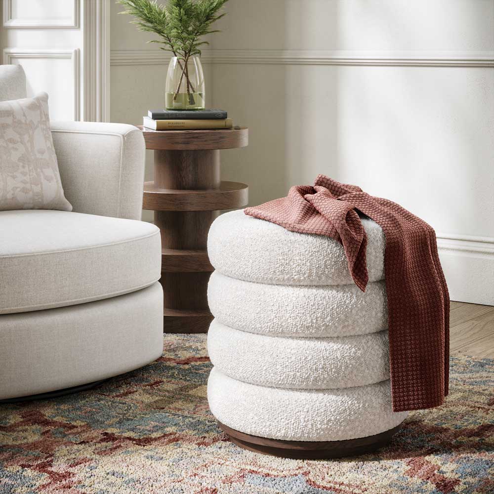 White textured footstool with a red blanket in a living room setting.