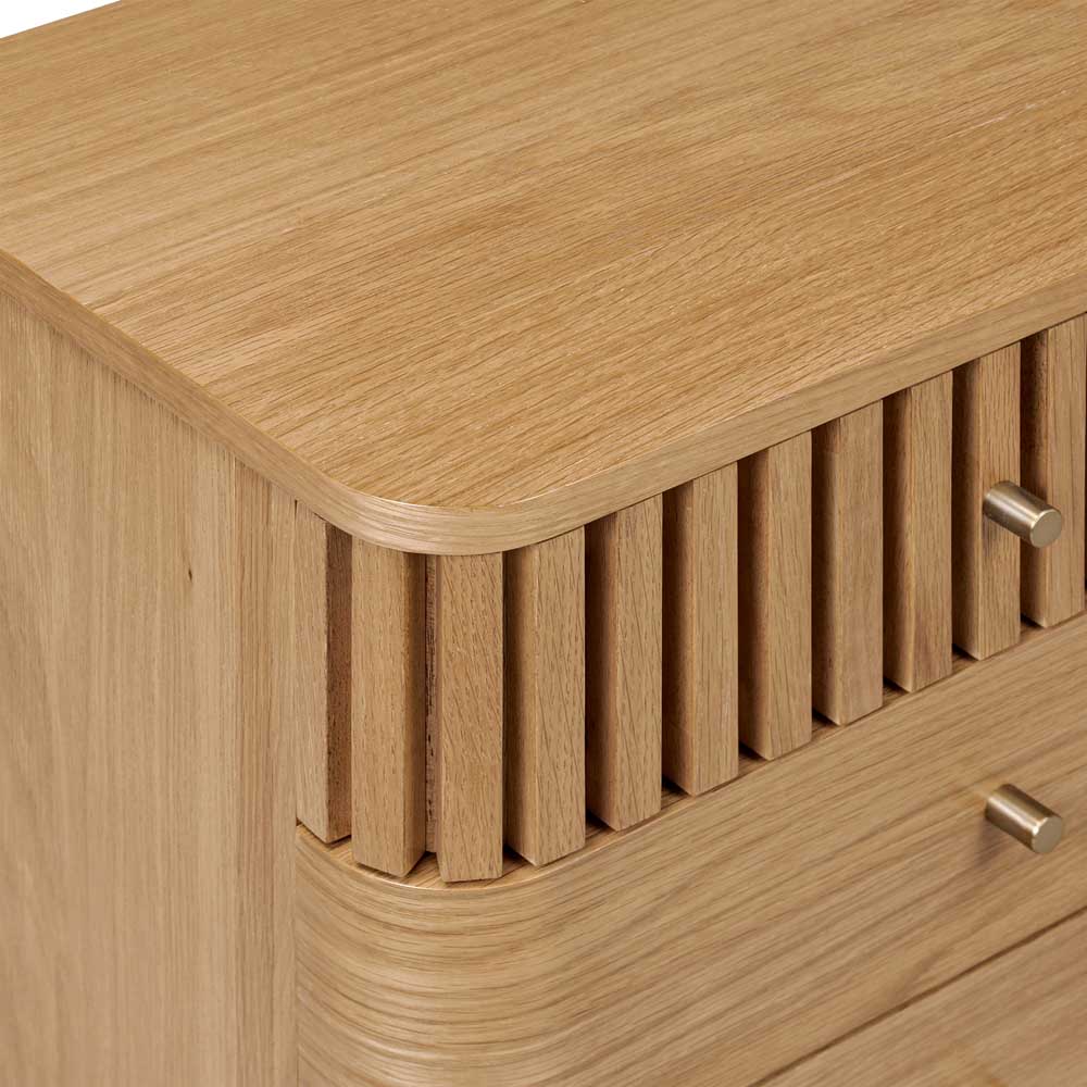 Wooden drawer with a slatted design and metallic handles on a wooden bedside locker.
