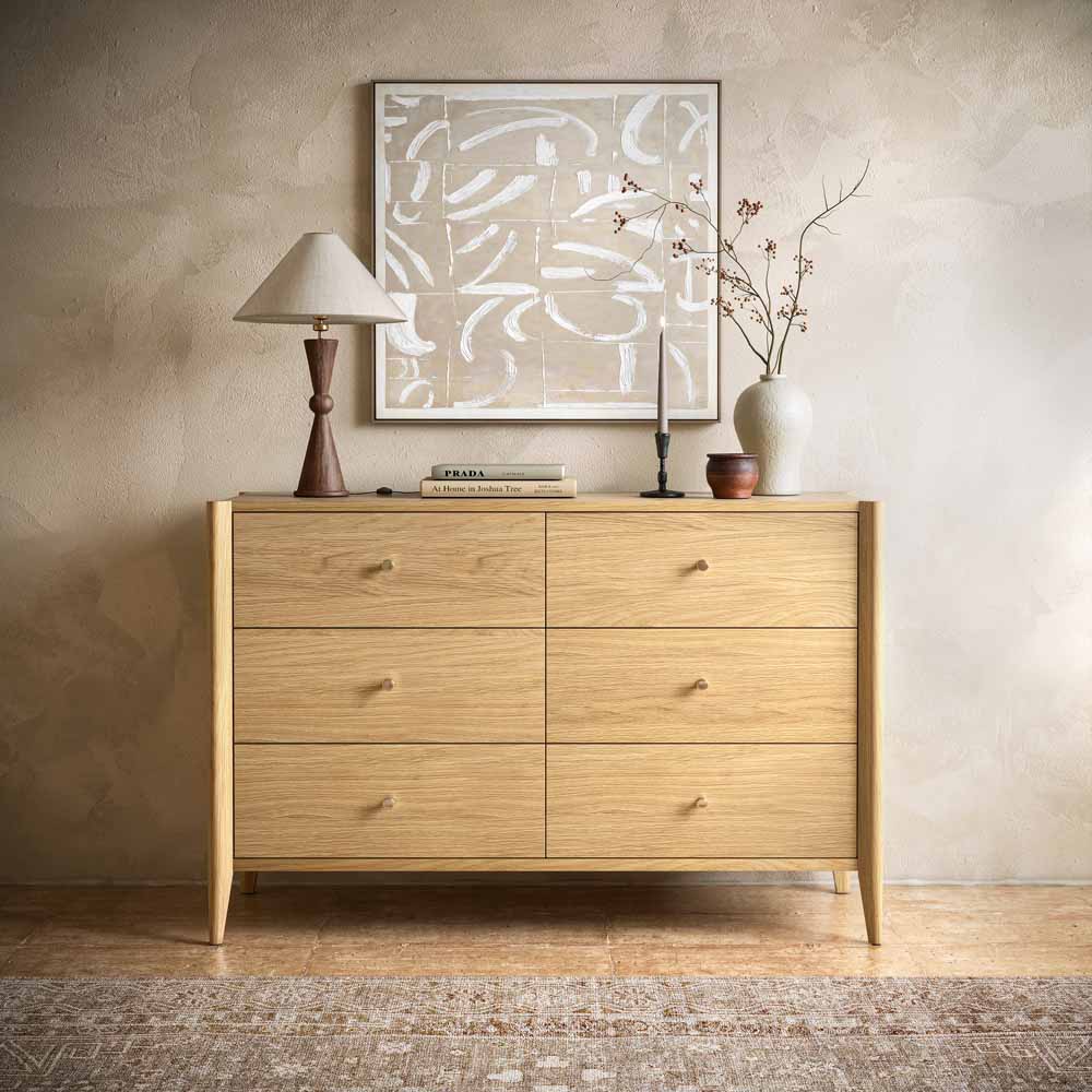 Natural Oak 6 drawer Wooden dresser with decorative items against a beige wall