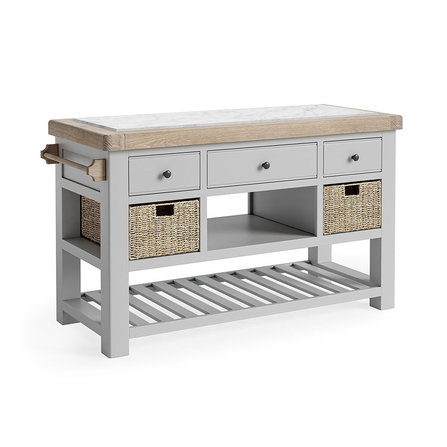 Oak Kitchen Island, oak and marble top. Underneath the storage has been broken into three section. First, 3 grey drawers, next, an open storage space flanked by a storage basket on either side, finally a completely open storage section with grey wooden slats. there is also a towel rail on the left side.