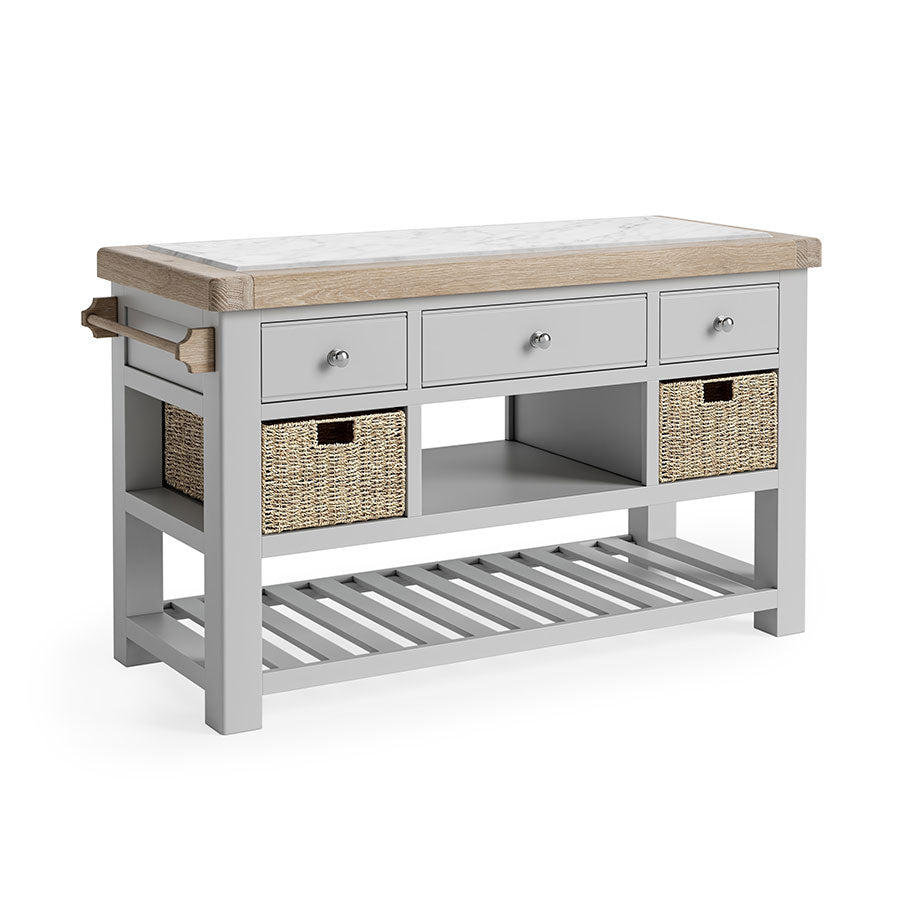 Oak Kitchen Island, oak and marble top. Underneath the storage has been broken into three section. First, 3 grey drawers, next, an open storage space flanked by a storage basket on either side, finally a completely open storage section with grey wooden slats. there is also a towel rail on the left side.